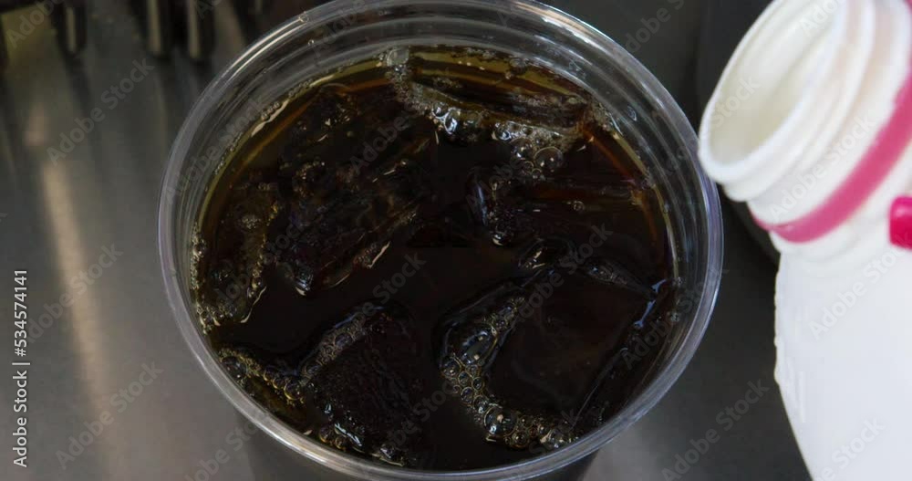 Closeup shot of barista adding milk to an iced coffee drink. Closeup shot of barista adding milk to an iced coffee drink.