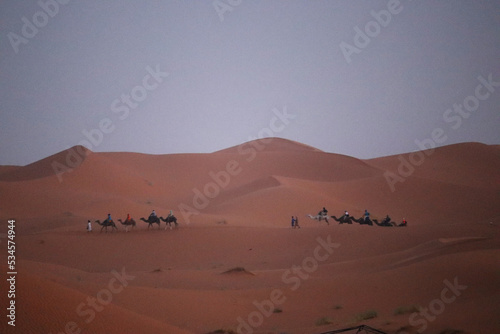 People riding a dromedary in the desert of Merzouga (Morocco)