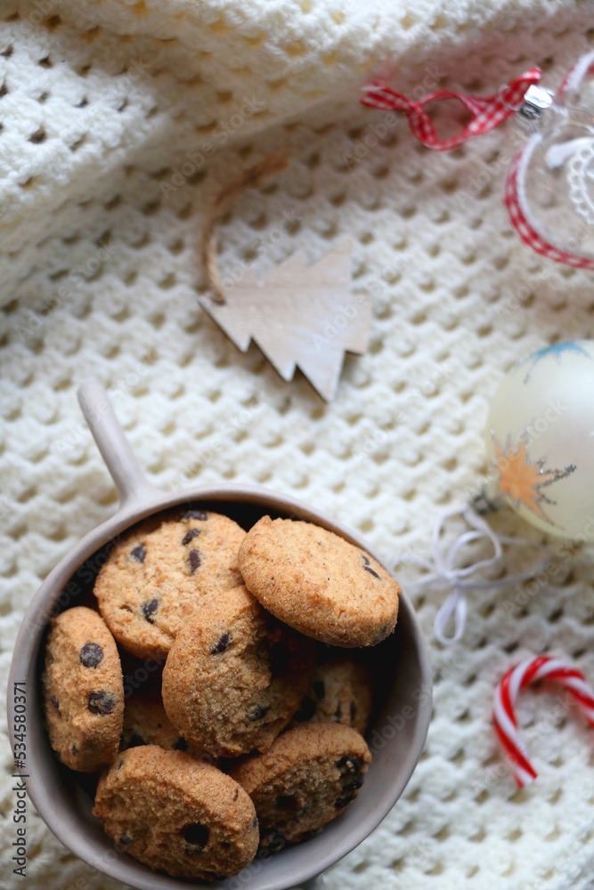 Bowl of cookies, soft knitted blanket and colorful Christmas ornaments at home. Flat lay. Bowl of cookies, soft knitted blanket and colorful Christmas ornaments at home. Flat lay.