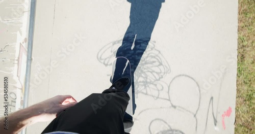 POV of Man on Skateboard Pushing and Riding on Warm Day at Skate Park photo