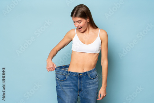 Woman astonished with results of her slimming and weight loss pulling large oversize jeans