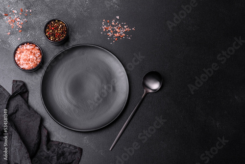 Empty black plate over dark stone background with free space. Top view photo