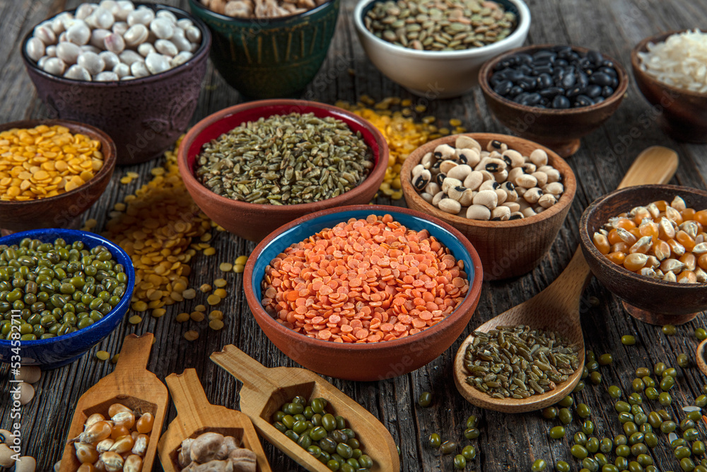 Vegan protein source.Various assortment of legumes, lentils, chickpea and beans assortment in different bowls on wooden table. Top view.