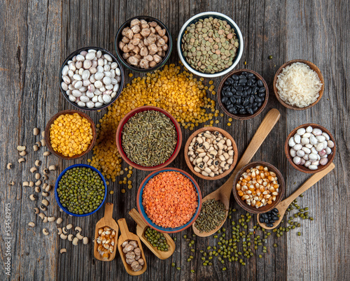 Vegan protein source.Various assortment of legumes  lentils  chickpea and beans assortment in different bowls on wooden table. Top view.