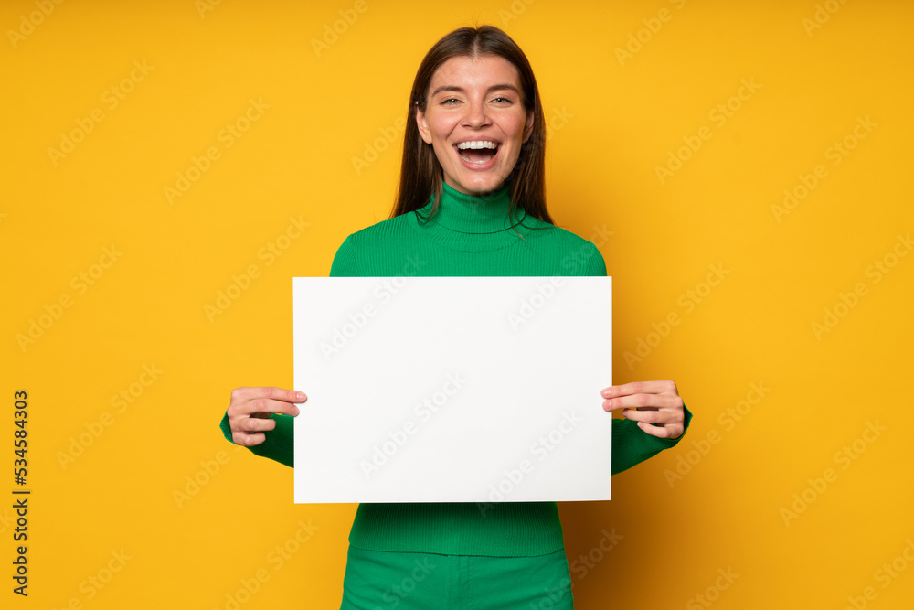Excited teacher showing big paper sheet with copy space to students on yellow background Excited teacher showing big paper sheet with copy space to students on yellow background