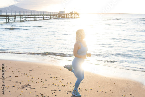Attractive fit woman practicing side lunges  exercising on the beach on a bright sunny day. Healthy lifestyle  outdoor workout