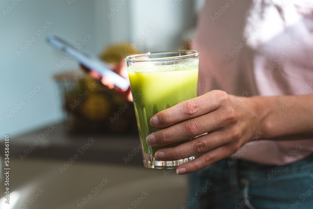 Unrecognizable woman drinks a fresh green healthy smoothie and uses a mobile phone. Unrecognizable woman drinks a fresh green healthy smoothie and uses a mobile phone.