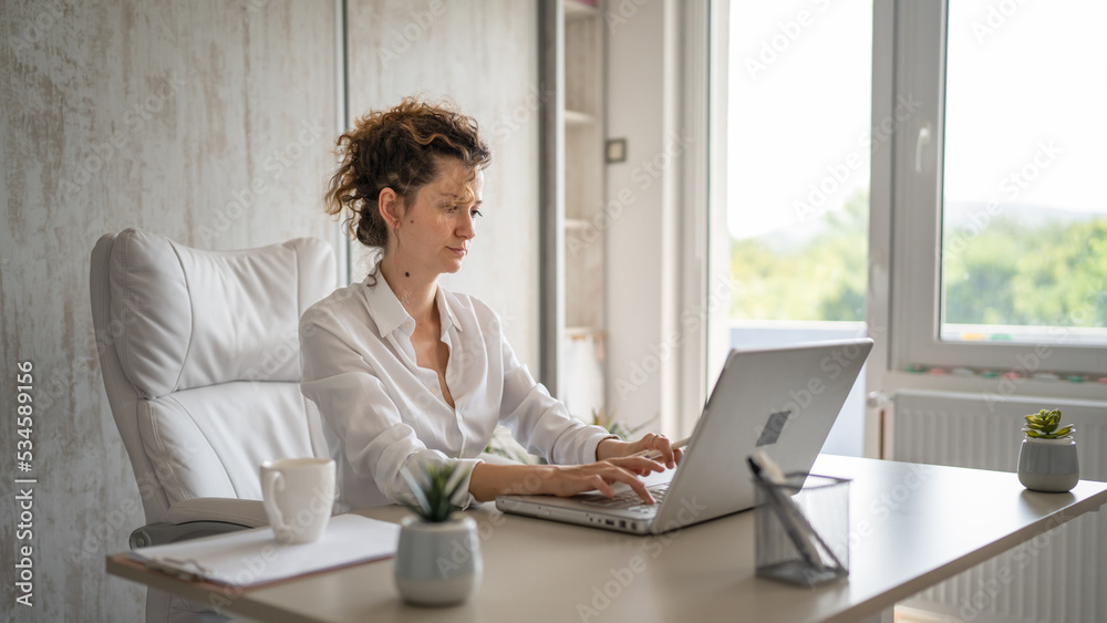 One young business woman back to work in the office working on laptop One young business woman back to work in the office working on laptop