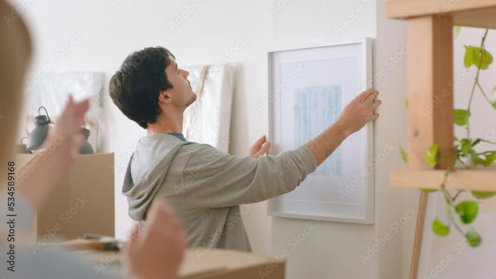 Home and painting for interior design after moving to new building, flat or apartment. Man, couple and art hanging on wall of lounge, happy together to decor in study, living room or office of house