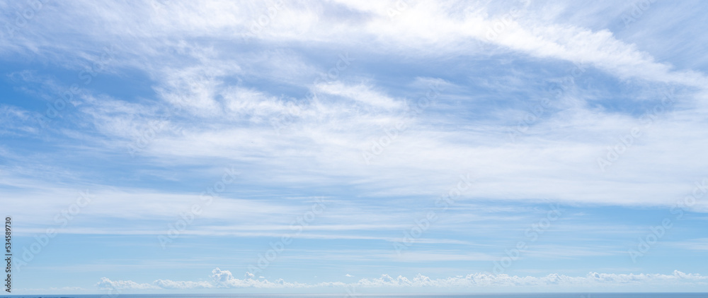 Airy blue sky with feathery white clouds over the sea