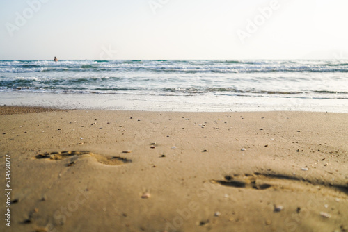 footprint on beach sand near sea, sunset, selective focus