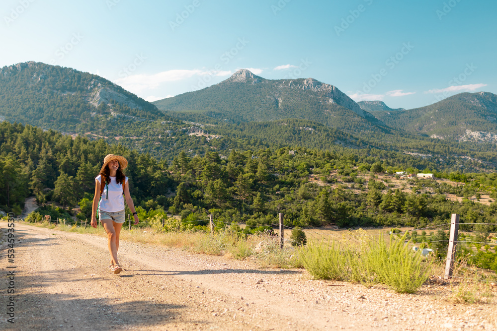 girl traveler with a backpack goes along a mountain path..