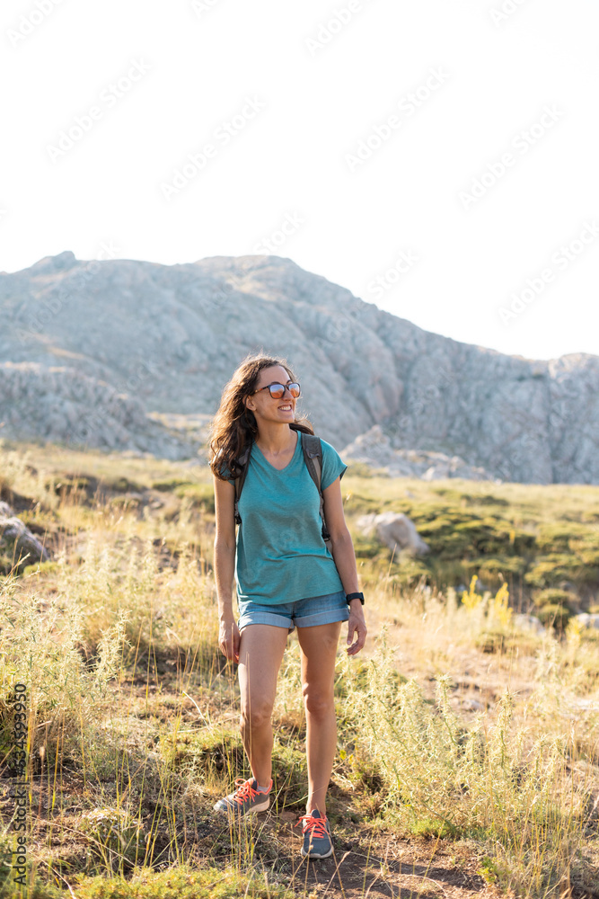 young girl with a backpack walks along a mountain path
