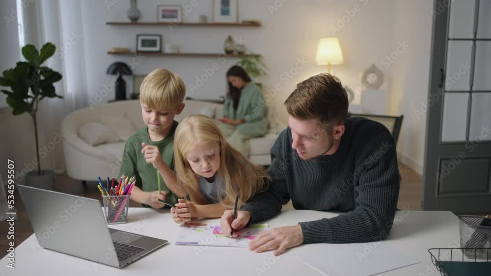 Father helping her children to do their homework. Cute siblings doing their homework studying with their mother at home parent child bonding, school assignments. Father helping her children to do their homework. Cute siblings doing their homework studying with their mother at home parent child bonding, school assignments.