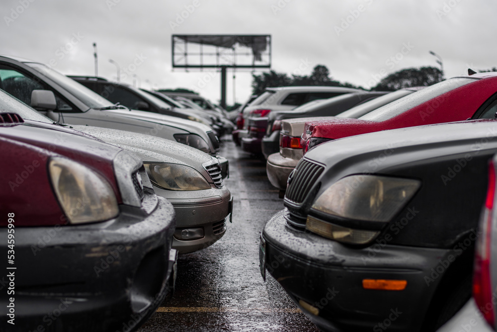 View from the back, from the side, of parked vehicles in the rain in Owerri, South of Nigeria on September 21, 2022 - cars in a lot