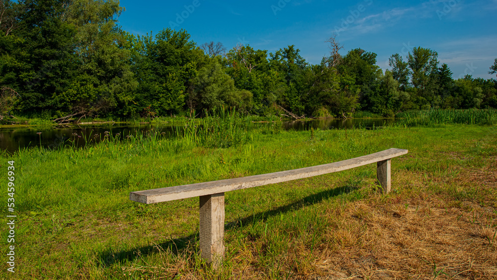 Wooden bench in a recreation area on the river bank.