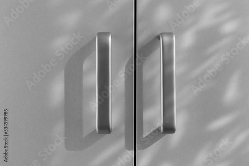 A pair of simple cabinet handles are grey and shade on a light background. Black and white