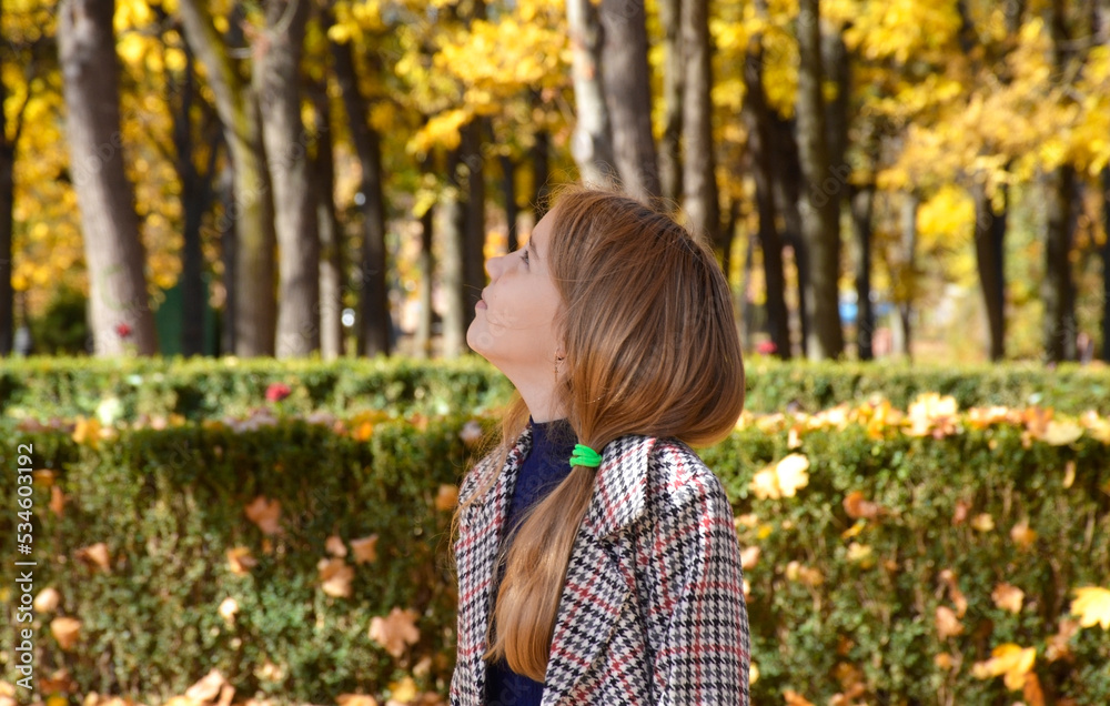 Beautiful fashionable girl with long blond hair in a stylish coat posing in the autumn park. Outdoor portrait. Women's autumn fashion concept