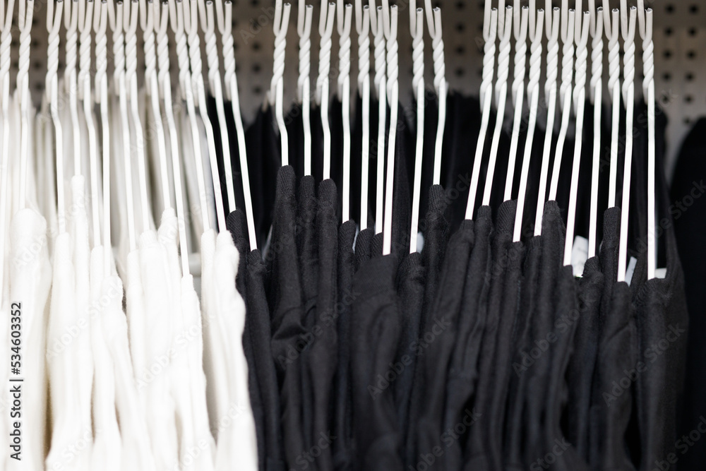 White and black t-shirts on hangers in a store