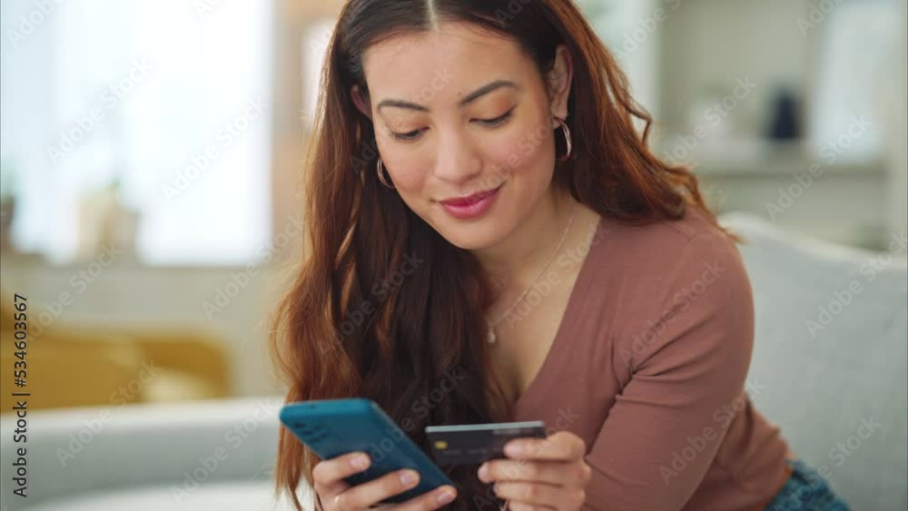 Woman, credit card and phone for e commerce, online shopping and fintech bank app on house or home living room sofa. Smile, happy and relax customer on technology Vietnamese ecommerce retail website