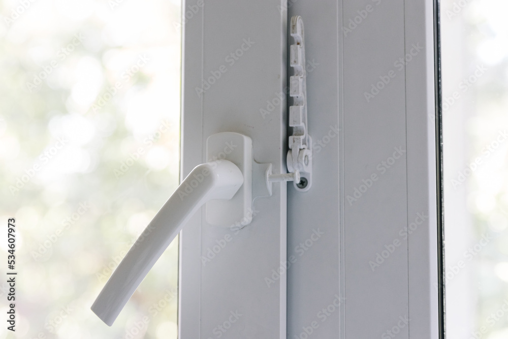 Close-up of a balcony door handle, double-glazed window fixing with a latch and a comb, a door frame. The concept of repairing doors and windows of a house