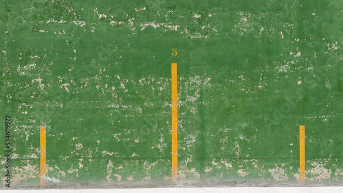 Lineas amarillas en pared verde desgasta con pintura desconchada en frontón photo