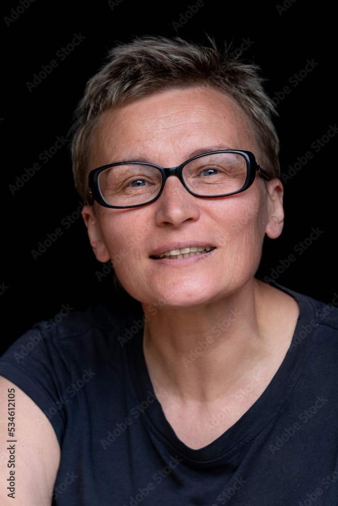 Portrait of caucasian woman with short haircut and black-rimmed glasses on black background, close-up. Emotions on face. High quality photo Portrait of caucasian woman with short haircut and black-rimmed glasses on black background, close-up. Emotions on face. High quality photo