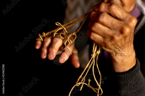 Hands of old woman with polyarthritis disease. Canvas strings on fingers of elderly lady, puppets. High quality photo photo