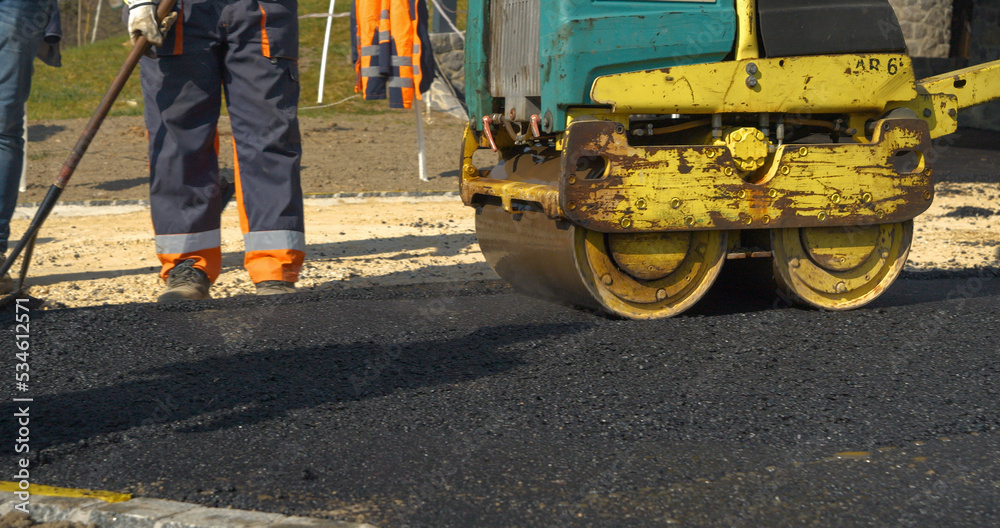 Working with asphalt roller for compacting and smoothing surface at driveway Working with asphalt roller for compacting and smoothing surface at driveway