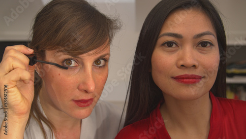 CLOSE UP: Two beautiful women using beauty products for applying face make up