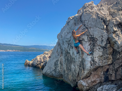 Picturesque seaside location with female climber at deep water solo climbing photo