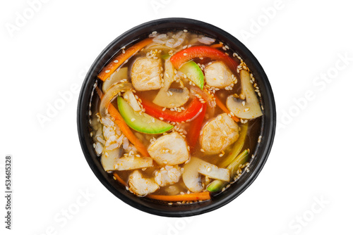 Instant soup, noodles wok, with vegetables, herbs and sesame. In a black round plate. On a white background.
