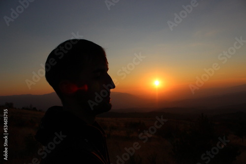 Silhouette of a young man on the sunset. Red sunset in the mountains 
