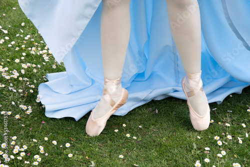 ballerina's legs in pointe shoes on a green flowering lawn in early spring
