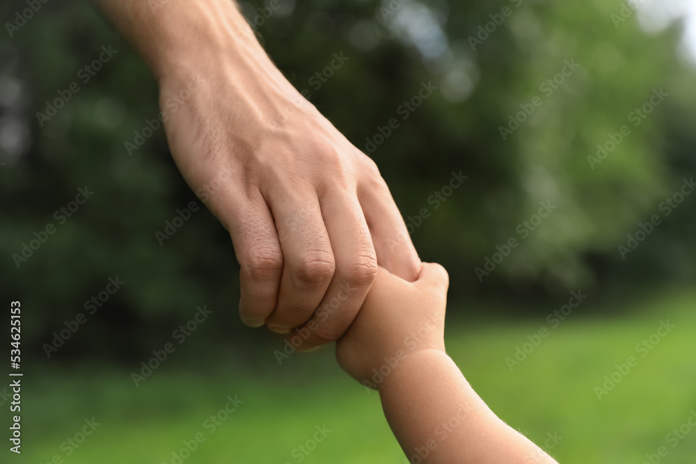 Daughter holding father's hand in park, closeup. Happy family Daughter holding father's hand in park, closeup. Happy family