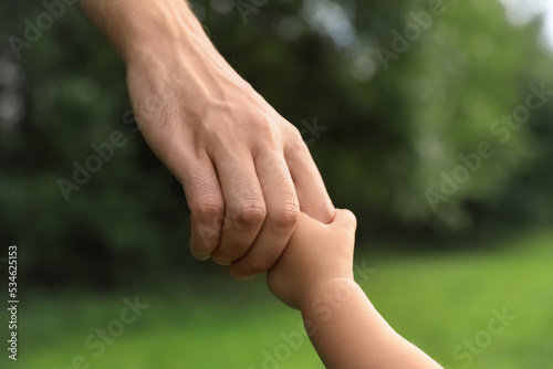 Daughter holding father's hand in park, closeup. Happy family © New Africa