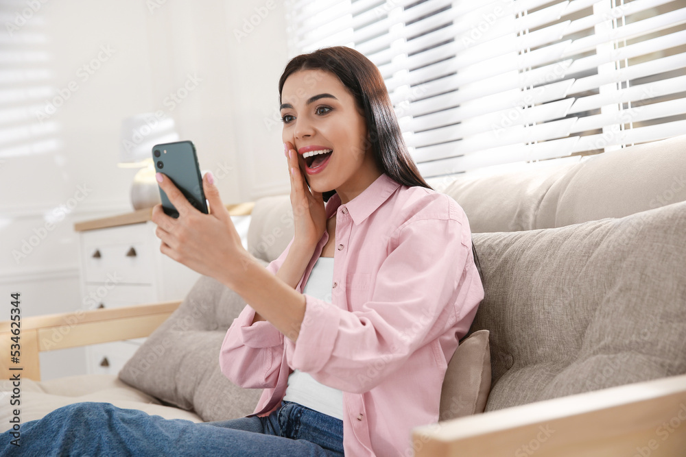 Emotional woman participating in online auction using smartphone at home Emotional woman participating in online auction using smartphone at home