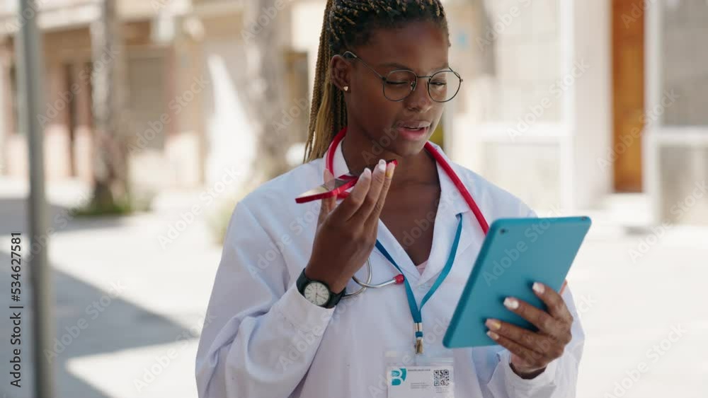 African american woman doctor talking on smartphone using touchpad at street African american woman doctor talking on smartphone using touchpad at street