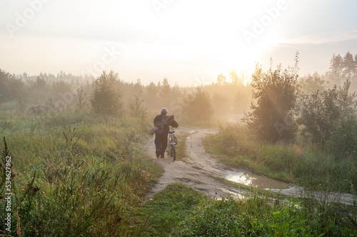 A man with a bicycle goes fishing on the road