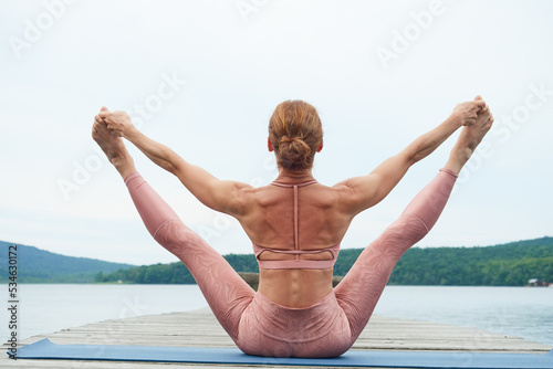 View from the back of a woman practicing yoga against the backdrop of a seascape