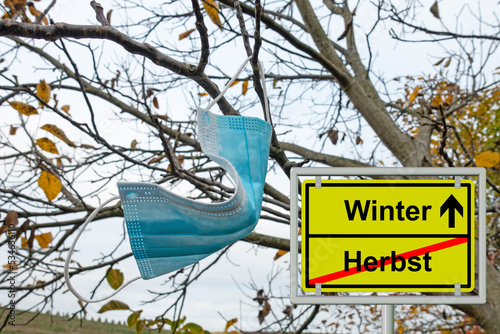 Mundschutzmaske am Baum hängend im Herbst photo