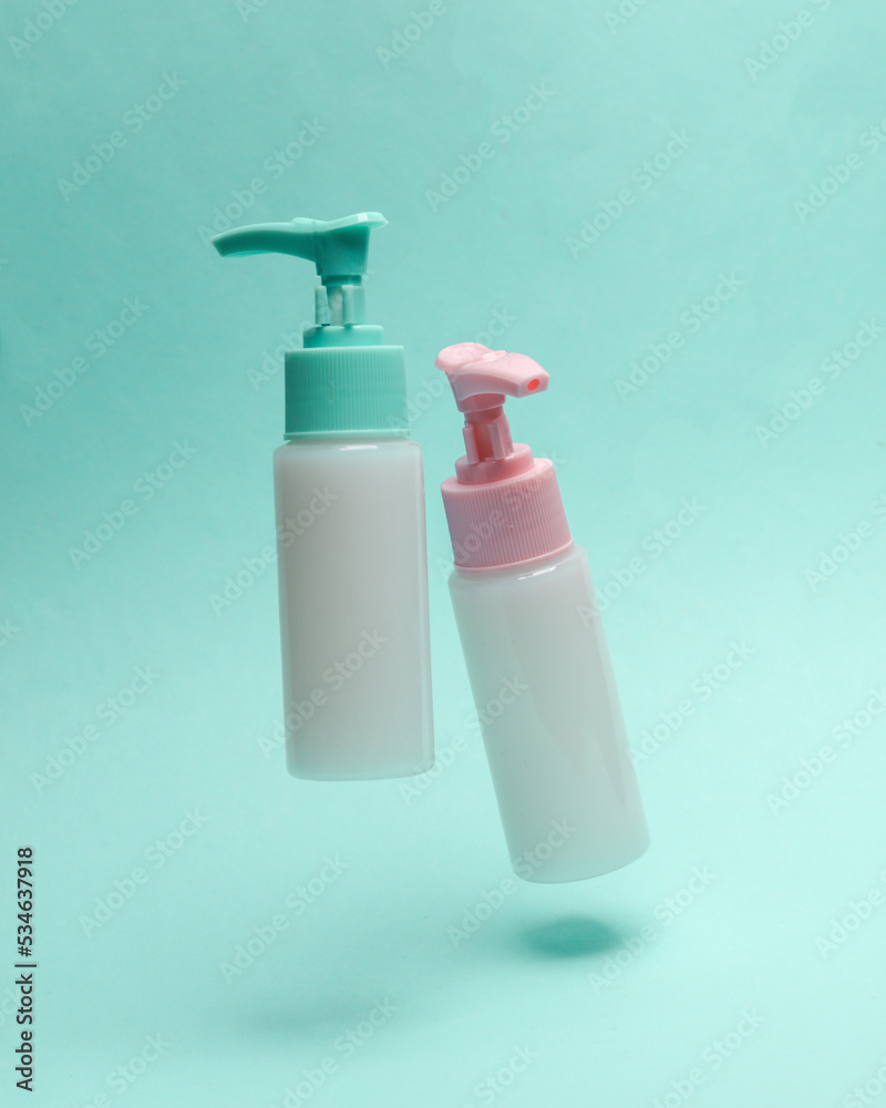 Bottles cream or liquid soap with dispenser levitating on a blue background Bottles cream or liquid soap with dispenser levitating on a blue background