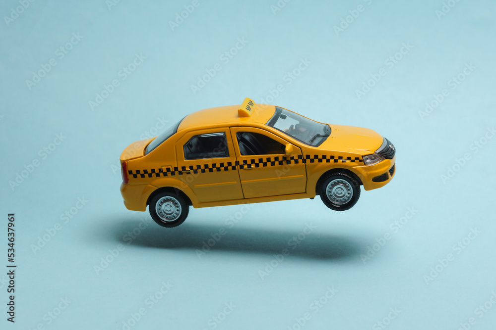 Miniature taxi car levitating on a blue background with a shadow Miniature taxi car levitating on a blue background with a shadow