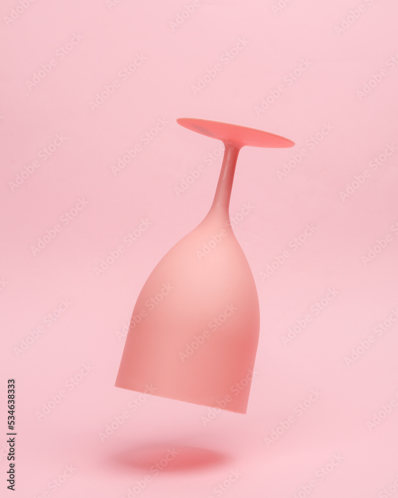 Pink plastic wine glass levitating on pink background Pink plastic wine glass levitating on pink background