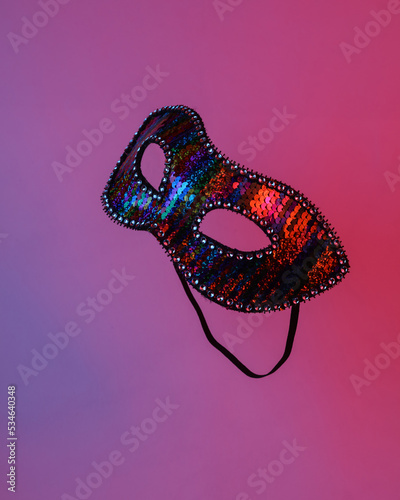 Carnival Venetian mask floating in the air, isolated in blue-red neon gradient light. Levitating objects. Minimal concept
