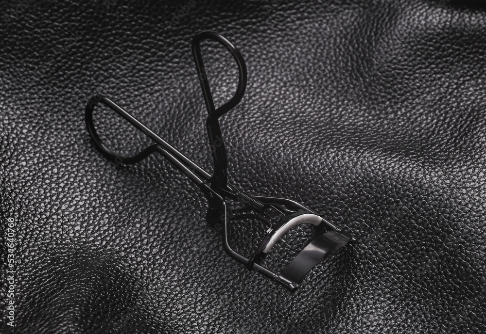 eyelash curler on black leather background