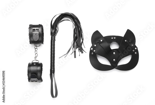 Leather handcuffs and whip with mask from sex shop on white background. Top view. Flat lay