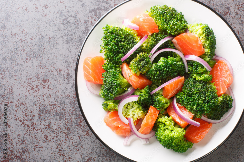 Fresh healthy salad of boiled broccoli, smoked salmon and red onion close-up in a plate on the table. horizontal top view from above Fresh healthy salad of boiled broccoli, smoked salmon and red onion close-up in a plate on the table. horizontal top view from above