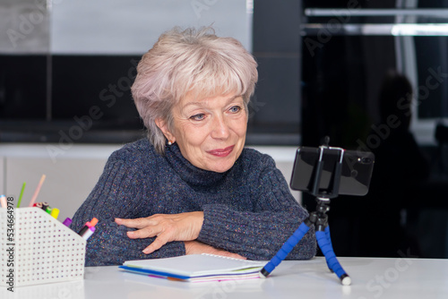 Obraz na plátně An elderly blonde woman in her 60s and 65s makes a video call, smiling happily