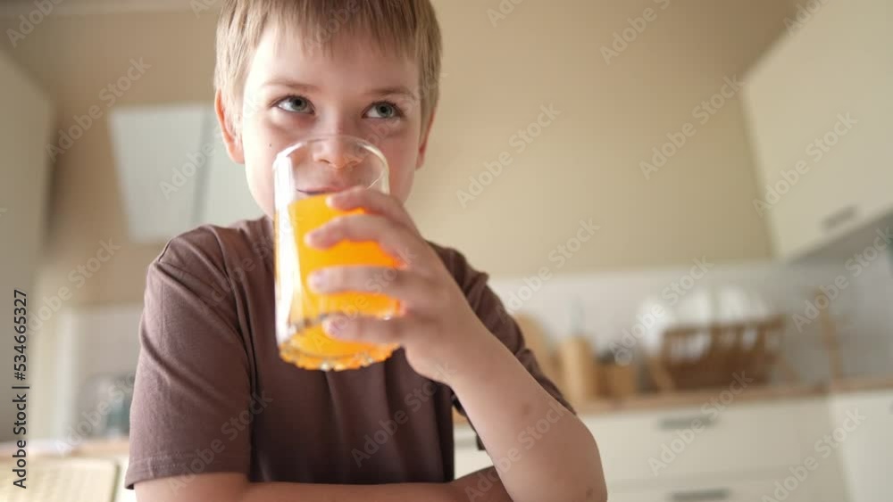 little boy drinks juice from a transparent glass cup. happy family kid dream concept. son child drinking juice in the morning for breakfast. drinking fresh juices lifestyle little boy drinks juice from a transparent glass cup. happy family kid dream concept. son child drinking juice in the morning for breakfast. drinking fresh juices lifestyle